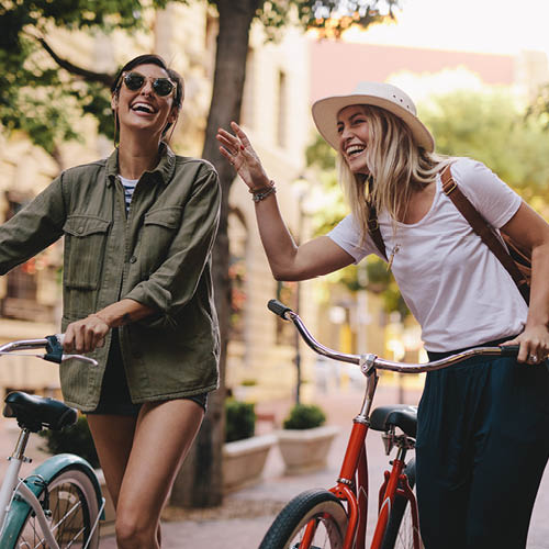 Zwei lachende Frauen schieben ihre Fahrräder