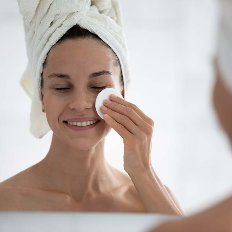 Een vrouw reinigt haar gezicht met een wattenschijfje