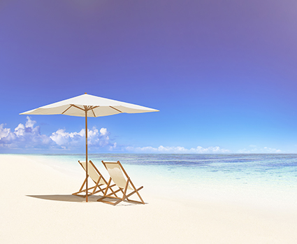 Zwei Liegestühle unter einem Sonnenschirm am Strand