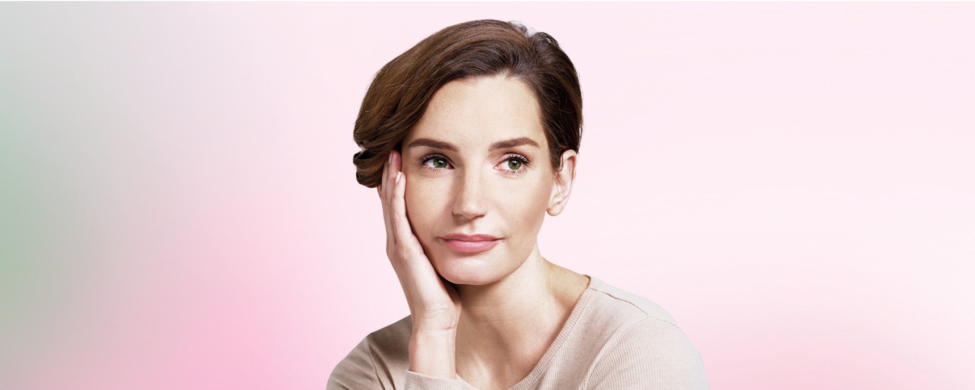 Woman with brunette, short hair in front of a green-pink background