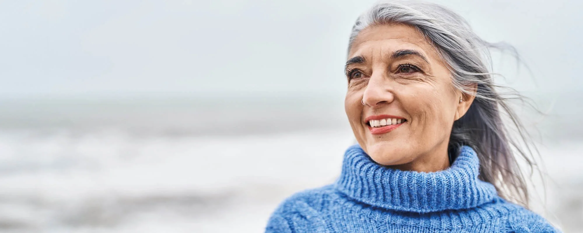 Grijze haren, glimlachende vrouw op het strand