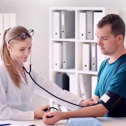 Ärztin misst den Blutdruck bei einem Patienten