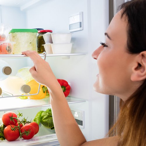 Frau schaut in ihren Kühlschrank