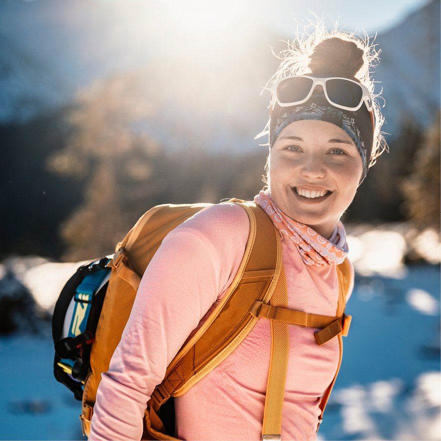 [Translate to Niederländisch:] Lächelnde Wintersportlerin in verschneiter Landschaft