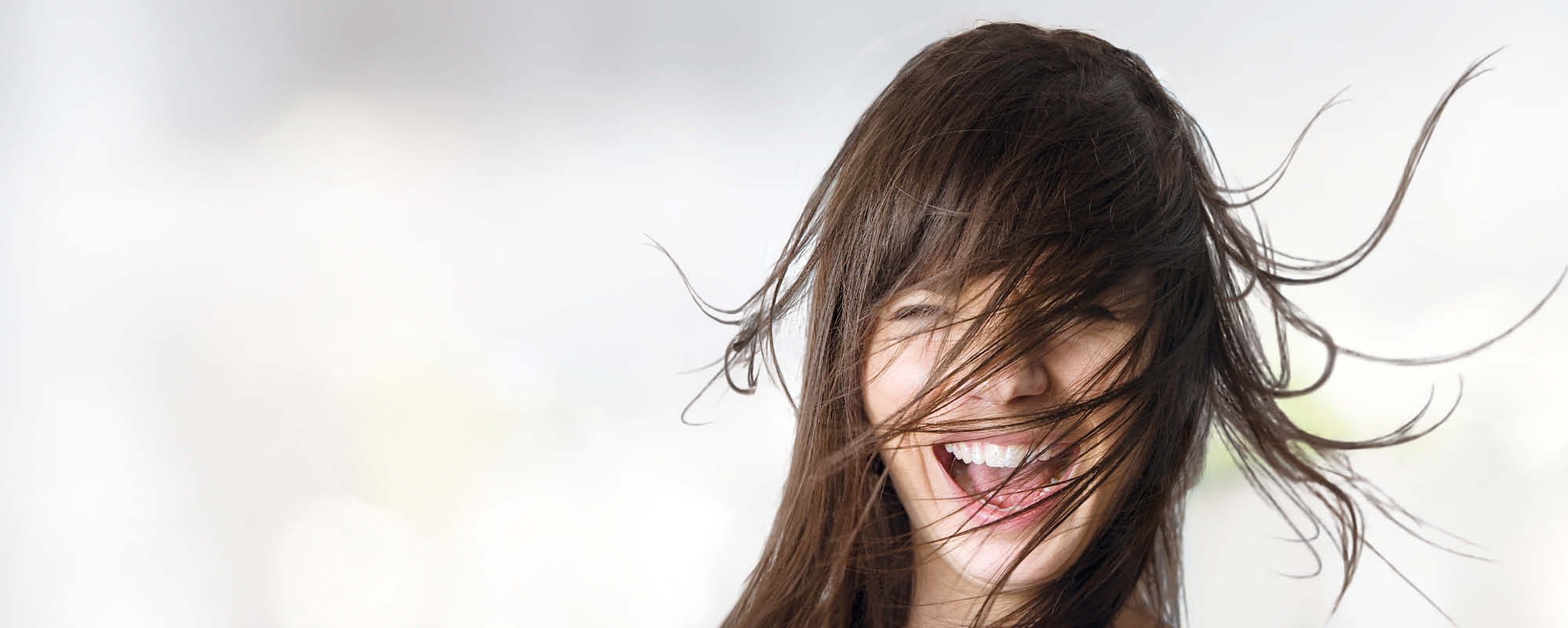 Het gezonde haar van de brunette vrouw waait over haar gezicht